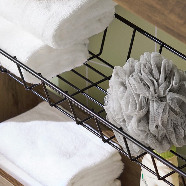 Handtücher und ein Badeschwamm in einem Drahtkorb im Badezimmerregal.