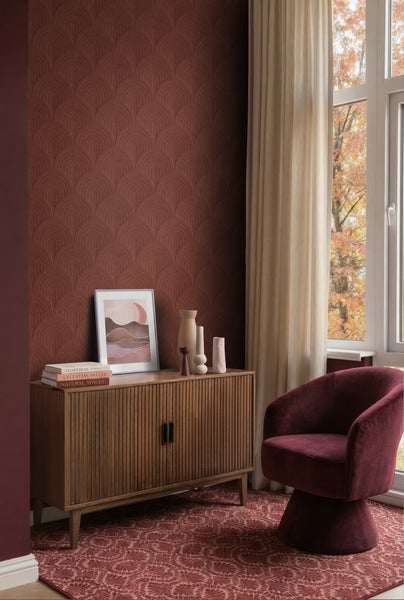 Modernes Wohnzimmer mit gemusterter Tapete mit Bogenmotiv, Sideboard aus Holz, rotem Samtsessel und gemustertem Teppich.