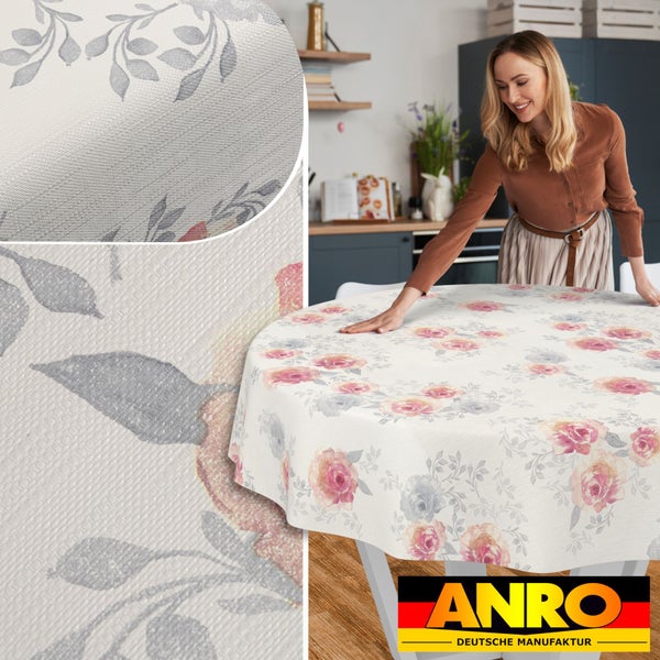 Runde Tischdecke mit floralem Muster aus Rosen und Blättern in einer hellen Küche, Detailansicht der Materialstruktur, ANRO Deutsche Manufaktur Logo.