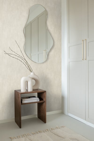 Dekoratives Zimmer mit einem unregelmäßig geformten Spiegel, einem Holztisch und einem Schrank