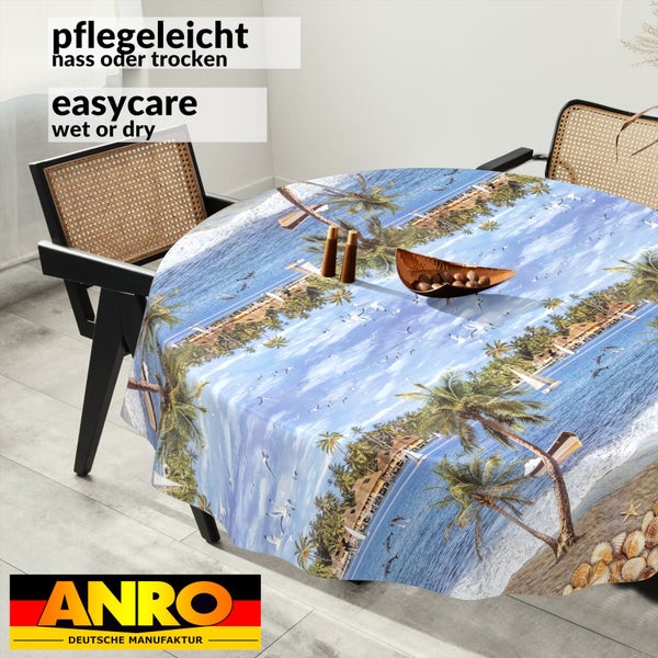 Rundes Tischtuch mit tropischem Strandmotiv, Palmen und Meer auf einem Esstisch. Pflegeleicht nass oder trocken. ANRO Logo.