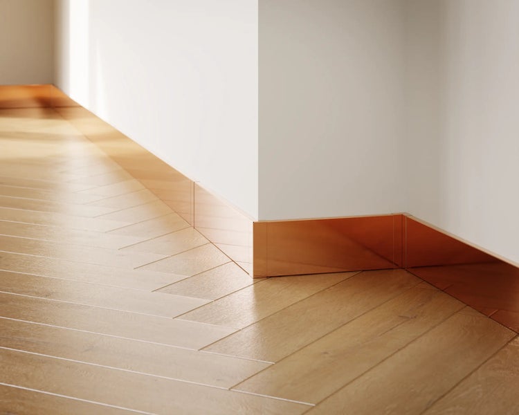 Innenaufnahme eines Raumes mit hellem Parkettboden in Fischgrätmuster und Sockelleisten