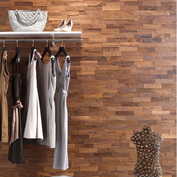Kleiderstange mit Kleidung, Handtasche und Schuhen vor einer Wandverkleidung