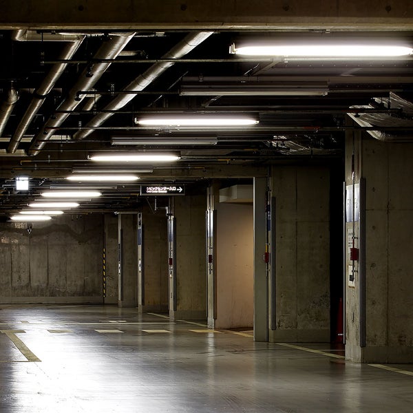 Beleuchtete Tiefgarage mit Betonwänden und Deckenrohren.