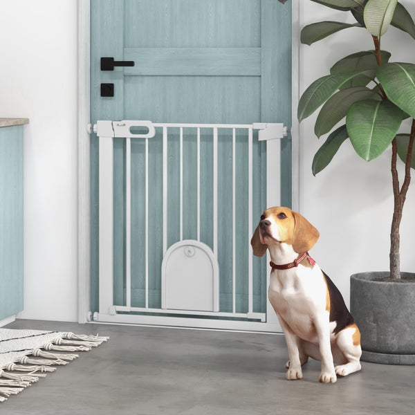Weißes Metall-Schutzgitter für Haustiere mit kleiner Tür, montiert im Türrahmen. Ein Beagle sitzt daneben in einem hellen, organisierten Raum.