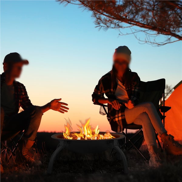 Zwei Personen sitzen um eine Feuerstelle im Freien.