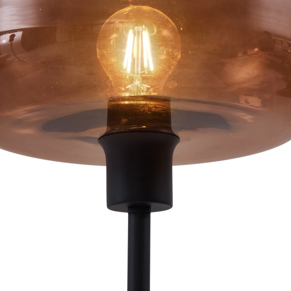 Detailaufnahme einer Leuchte mit bernsteinfarbenem Glasschirm und freiliegender Glühbirne.