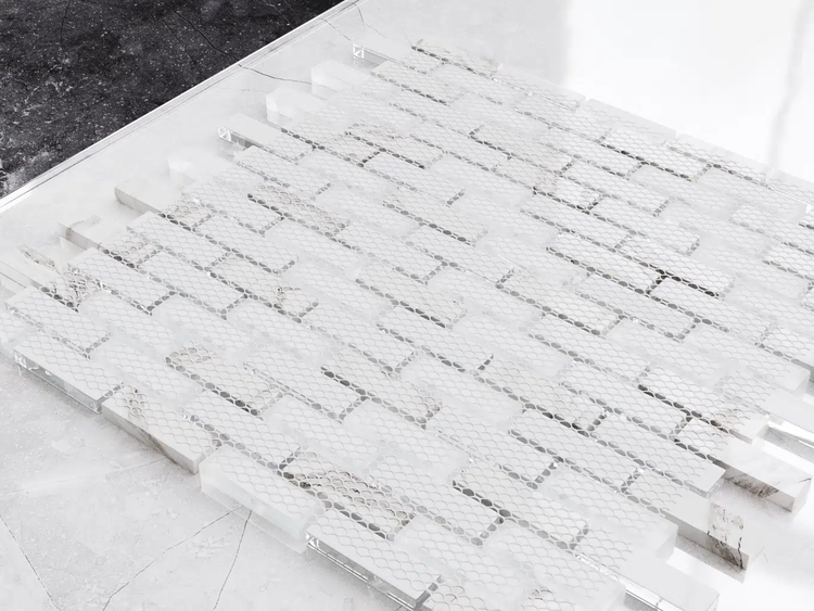 Weiße Mosaikfliesen aus Marmor in Stäbchenform mit unterschiedlichen Oberflächenstrukturen.