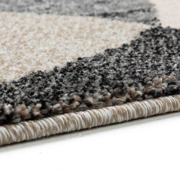 Nahaufnahme eines Teppichs mit geometrischem Muster, strukturiertem Flor und eingefasster Kante.