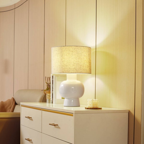 Tischlampe mit rundem Lampenschirm aus Stoff auf einer Kommode