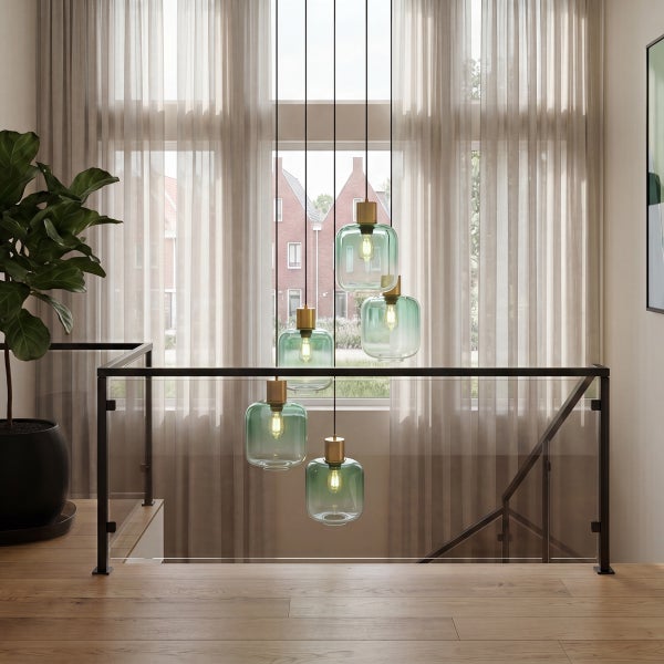Moderne Hängeleuchte mit fünf gläsernen Lampenschirmen in einem hellen Wohnbereich über einer Treppe mit Glasgeländer und Holzfußboden.