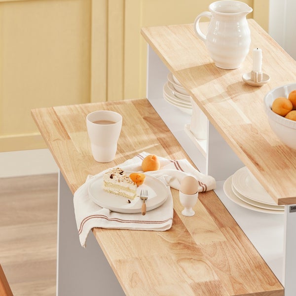 Gedeckter Tisch mit Frühstücksgeschirr, Kuchen, Obst und Getränken auf einer Holzplatte