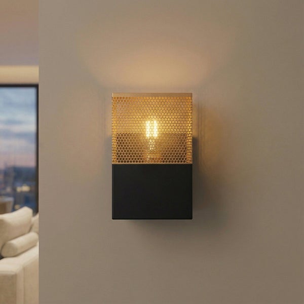 Moderne rechteckige Wandleuchte mit schwarzem Metallsockel und goldfarbenem Lochblech-Schirm, leuchtend an einer Wand montiert.