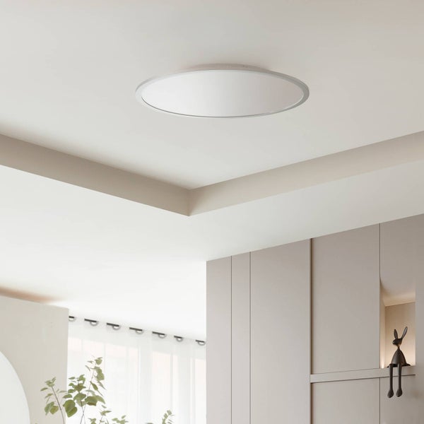 Runde flache LED Deckenleuchte montiert an einer hellen Decke in einem modernen hellen Raum mit minimalistischen Schränken.