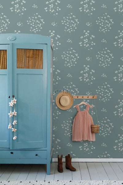 Zimmeransicht mit blauem Schrank, floraler Tapete, Hut, Kleid, Tasche und Stiefeln.