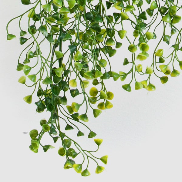 Künstliche grüne Hängepflanze mit kleinen, herzförmigen Blättern an dünnen Trieben.