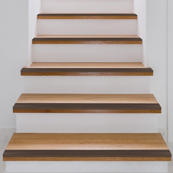 Holztreppe mit hellen Stufen und integriertem dunklen Anti-Rutsch-Streifen an der Vorderkante.