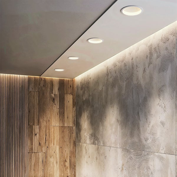 Moderne Innenansicht mit runden Deckeneinbaustrahlern und indirekter LED-Beleuchtung an einer Holz- und strukturierten Betonoptik-Wand.