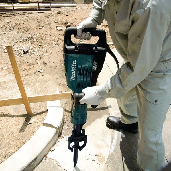 Eine Person benutzt einen Makita Abbruchhammer auf einer Baustelle, um Beton zu zerkleinern.