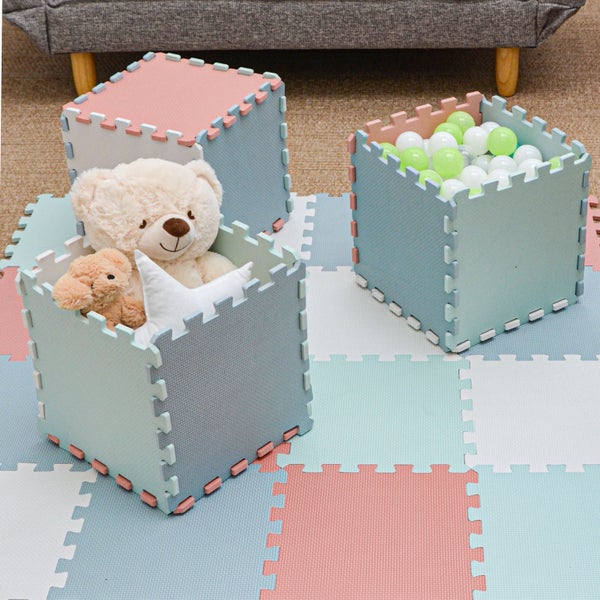 Ineinandergreifende Spielmatten aus Schaumstoff als Bodenbelag und zu Spielzeugboxen zusammengebaut mit Kuscheltieren und Bällen.
