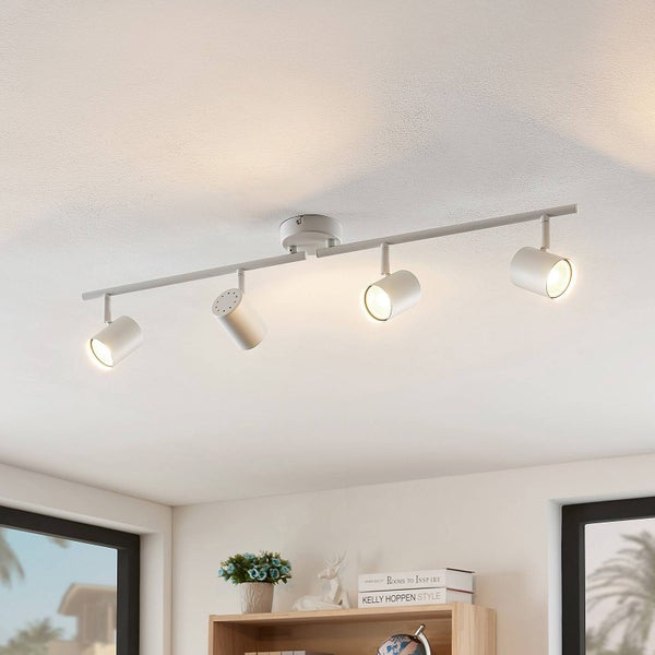 Moderne weiße Deckenleuchte aus Metall mit vier verstellbaren Strahlern an einer Schiene, montiert an einer hellen Decke über einem Holzregal.