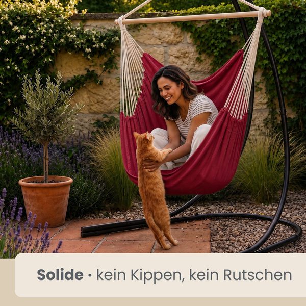 Frau sitzt in einem roten Hängesessel mit schwarzem Gestell im Garten und spielt mit einer Katze. Die Konstruktion ist standsicher und stabil.