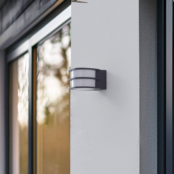 Moderne Außenwandleuchte in Anthrazit aus Metall und Kunststoff an einer Hauswand neben einem Fenster.