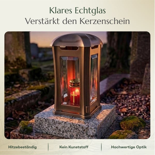 Grablampe aus Metall mit klaren Echtglasfenstern und einer brennenden Grabkerze auf einem Sockel.