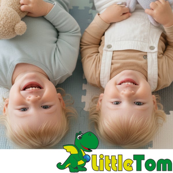 Zwei kleine Kinder liegen auf einer Puzzlematte auf dem Boden und halten Kuscheltiere, Little Tom Logo.