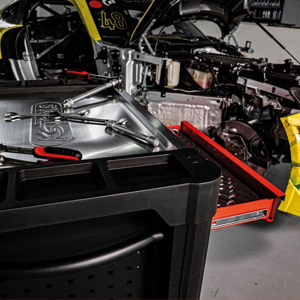 Werkzeugwagen mit Werkzeugen vor einem demontierten Auto