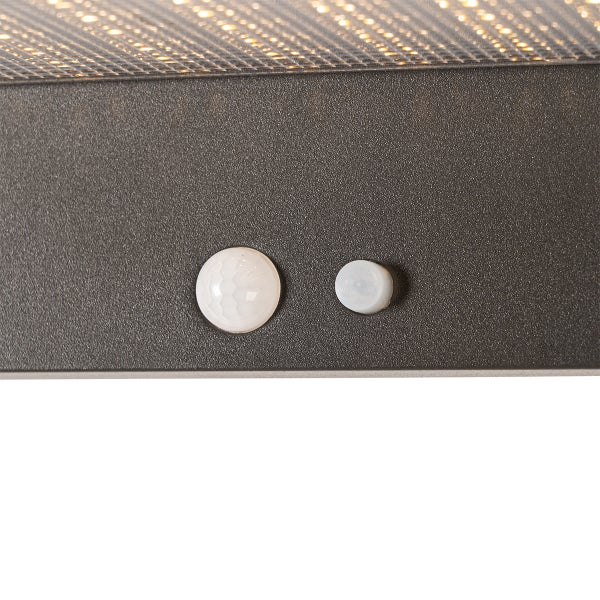 Nahaufnahme eines Bewegungssensors und Lichtsensors an einem texturierten anthrazitfarbenen Gehäuse einer Außenleuchte.