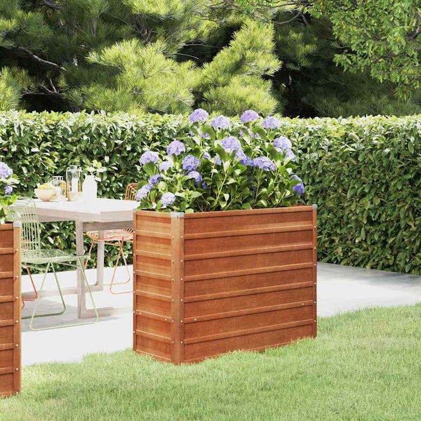 Hochbeet aus Holz im Garten mit Hortensien, daneben eine Terrasse mit Gartenmöbeln und eine Hecke.