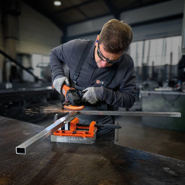 Fein VersaMAG Permanent-Magnet-Schraubstock spannt ein Metallwerkstück ein, geführt von einer Person mit Schutzhandschuhen.