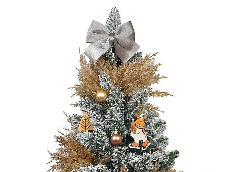 Geschmückter künstlicher Weihnachtsbaum mit künstlichem Schnee, Schleife, Christbaumkugeln und weihnachtlichen Holzanhängern.