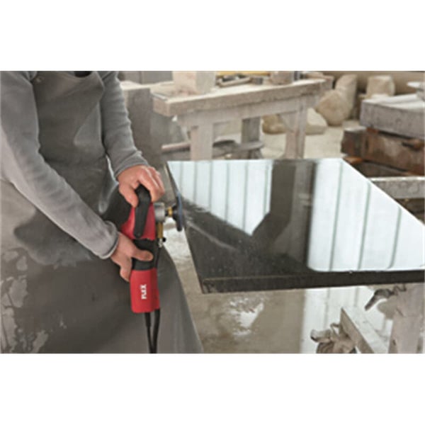 Handwerker bearbeitet die Kante einer Granitplatte mit einem Flex Winkelschleifer in einer Werkstatt.