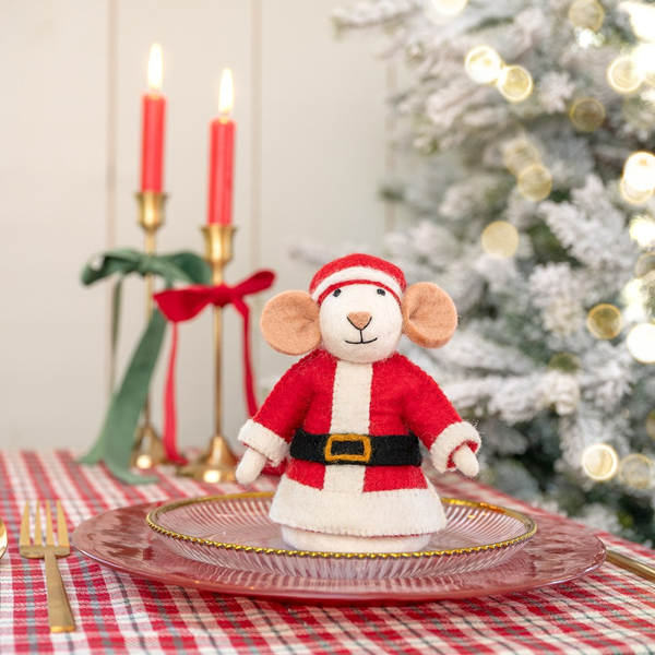 Dekorative Mausfigur im Weihnachtsmannkostüm auf einem gedeckten Tisch