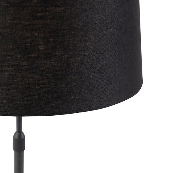 Nahaufnahme eines schwarzen Stofflampenschirms mit strukturierter Oberfläche auf einem schwarzen Metallständer.
