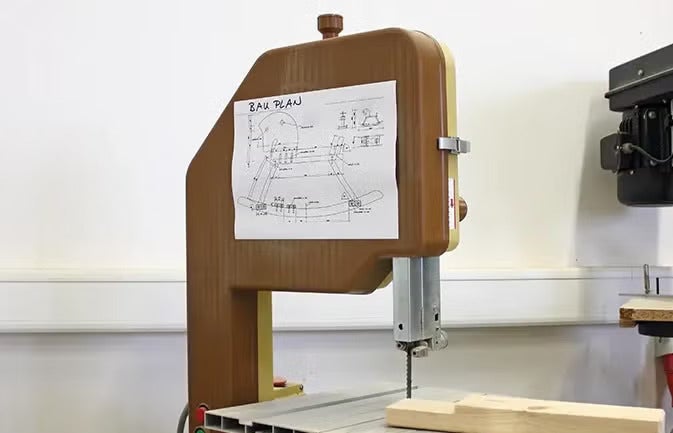 Bandsäge mit aufgeklebtem Bauplan für ein Schaukelpferd in einer Werkstatt.
