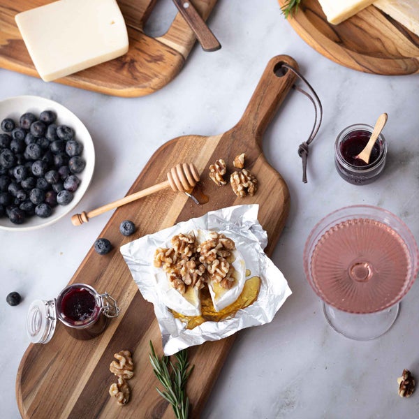 Szene mit Käse, Blaubeeren, Honig und Walnüssen auf Holzbrettern