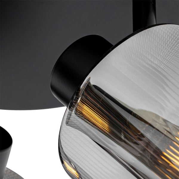 Detailaufnahme einer Deckenleuchte mit transparentem Glasschirm und schwarzer Halterung