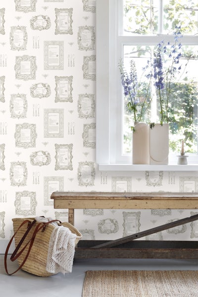 Szene mit gemusterten Tapeten, Holztisch und Dekorationselementen in einem hellen Raum.