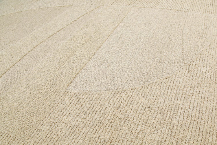 Nahaufnahme eines beigen Teppichs mit geometrischem 3D-Muster aus Linien und Kreisen mit verschiedenen Florhöhen.
