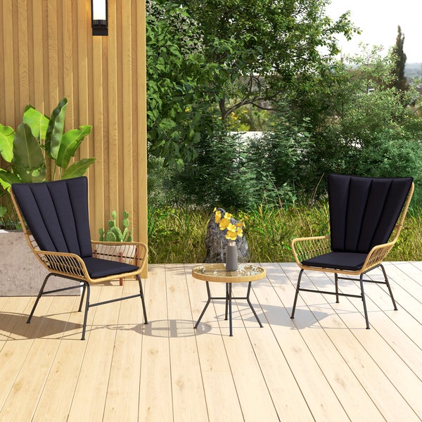 Gartenszene mit zwei Rattansesseln, einem Beistelltisch und üppigem Grün