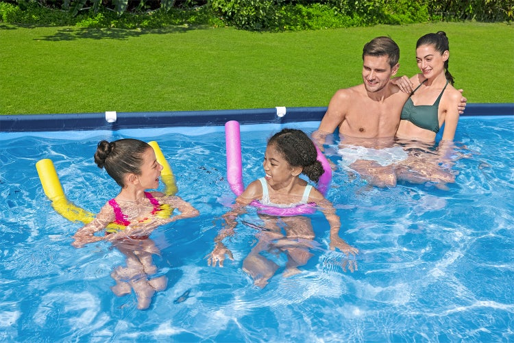 Helle Szene einer Familie mit Kindern in einem Rahmenpool im Garten mit Poolnudeln aus Schaumstoff im Wasser.