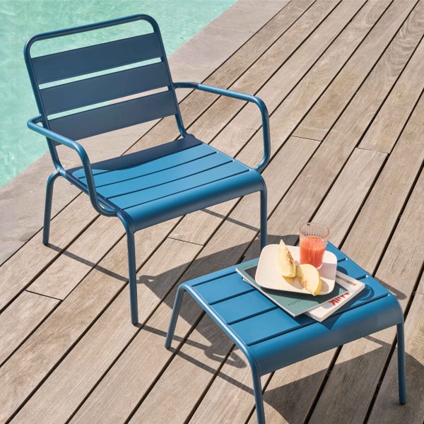 Blauer Garten-Lounge-Sessel und Beistelltisch aus Metall mit Latten-Design auf einer Holzterrasse am Pool.