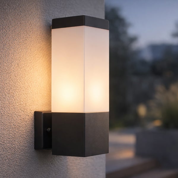 Moderne rechteckige Außenwandleuchte in Anthrazit mit weißem Diffusor, montiert an einer Wand und warmweiß leuchtend.