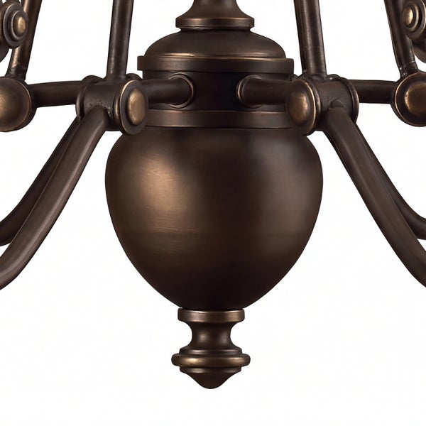 Detailaufnahme des bronze-farbenen, vasenförmigen Mittelteils eines klassischen Kronleuchters aus Metall mit geschwungenen Armen.