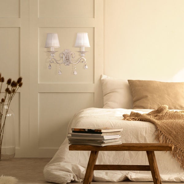 Wandleuchte mit zwei Lampen und Kristallanhängern im Schlafzimmer.