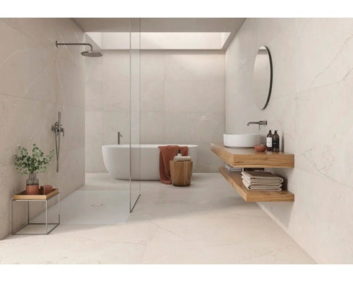 Modernes, helles Badezimmer mit großformatigen Fliesen in Marmoroptik, freistehender Badewanne, begehbarer Dusche mit Glaswand und Holzwaschtisch.