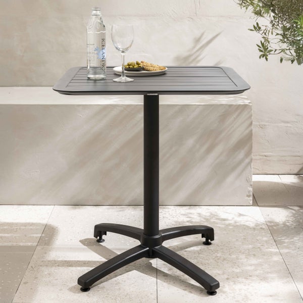 Quadratischer Gartentisch in Anthrazit mit Lattenoberfläche und Mittelfuß auf einer hellen Terrasse.